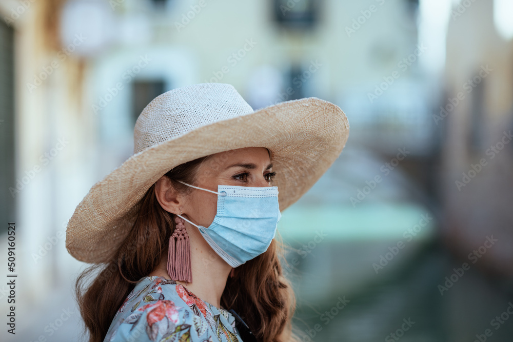Φωτογραφία stylish woman in floral dress with hat and medical mask