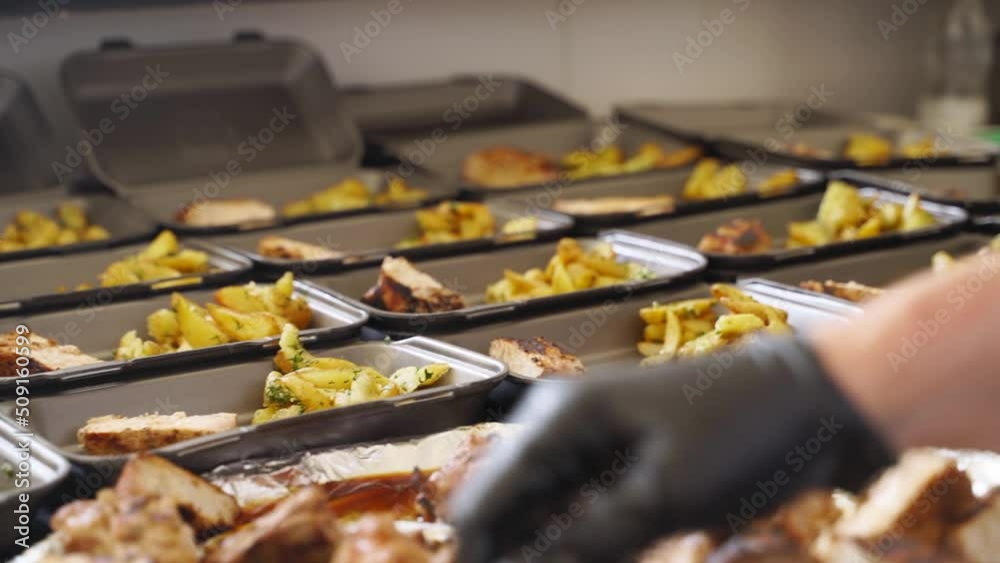 Volunteers put food in takeaway plastic containers for humanitarian aid to refugees. Online order in disposable lunch boxes amid COVID-19. Meal delivery service. Food donation. Local Food Bank.