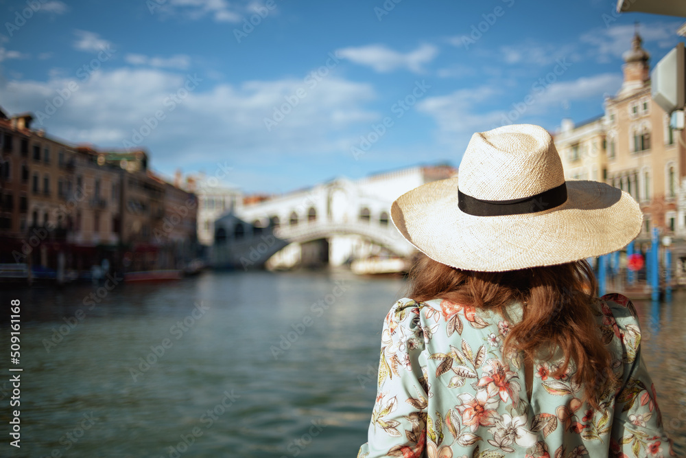 Seen from behind young woman in floral dress with hat