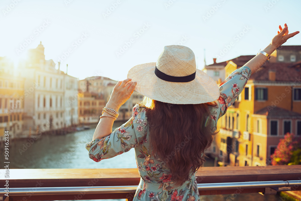 Fototapeta premium Seen from behind elegant traveller woman in floral dress