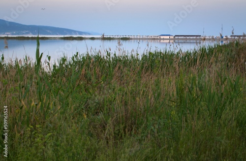 Beautiful seascape at sunset. Blue sky. Mirror surface of water. Mountain ranges in the distance on the horizon. Aleksino beach. Novorossiysk. Russia.