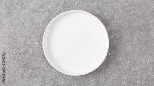 Empty white plate on gray concrete background, menu concept