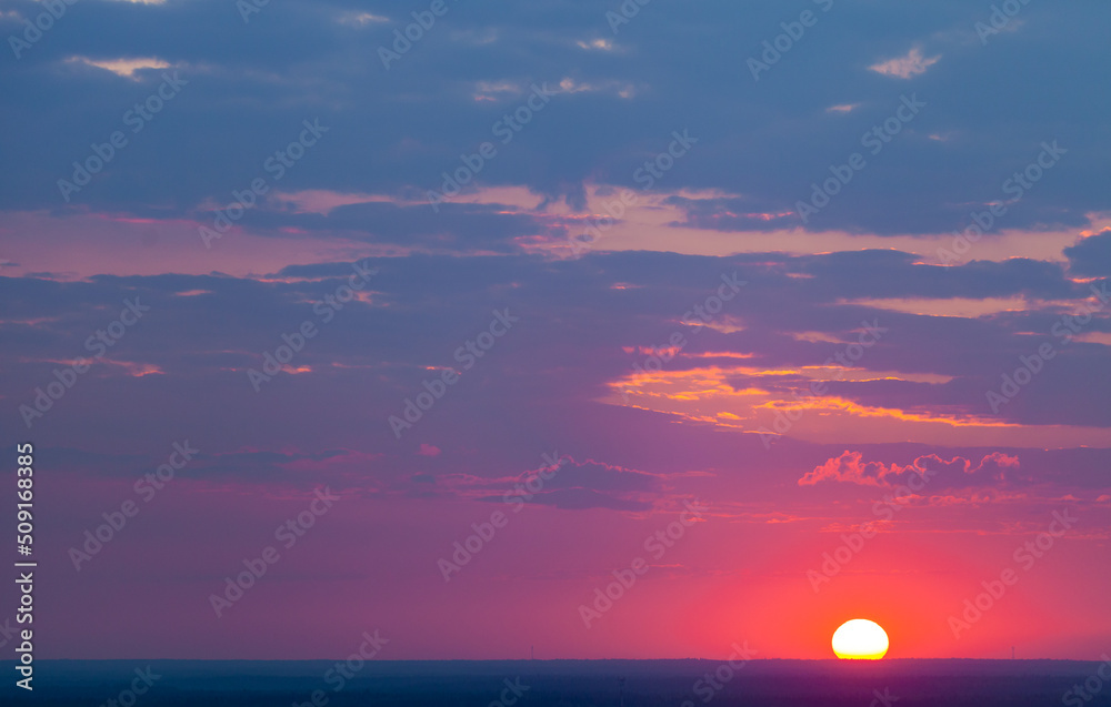 Beautiful sunset with a huge sun and multi -colored clouds.