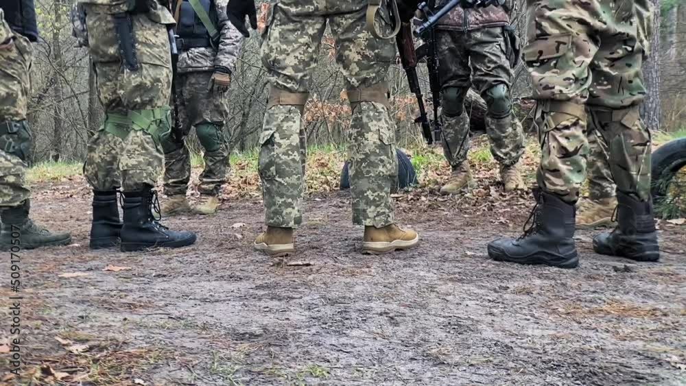 Soldiers of the intelligence forces of the Ukrainian army stand in a clearing with weapons in camouflage clothes. Soldiers of the Special Forces discuss a tactical task. Soldiers of the intelligence forces of the Ukrainian army stand in a clearing with weapons in camouflage clothes. Soldiers of the Special Forces discuss a tactical task.
