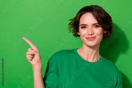 Photo of pretty sweet young lady dressed casual t-shirt pointing empty space isolated green color background