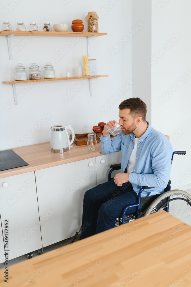 Fototapeta premium Young Disabled Man On Wheelchair In The Kitchen.