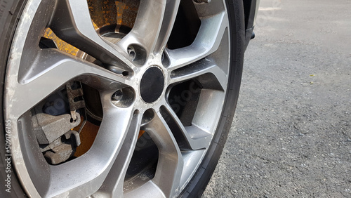 The original alloy wheel, dirty and scratched on the car close-up. Worn car wheels are waiting for repair. selective focus. Car repair and restoration concept required. Damaged car wheel.