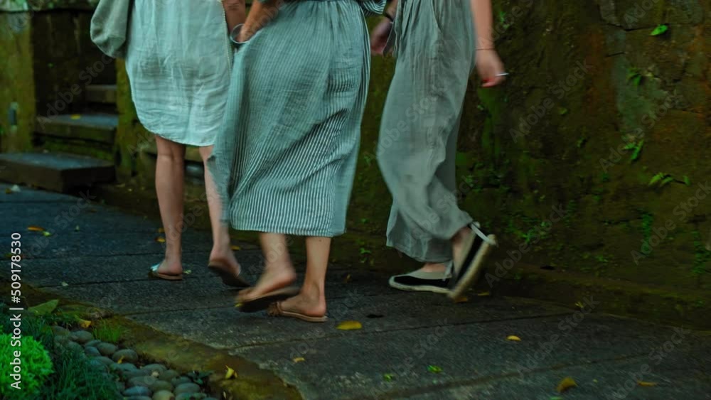 Legs of European girls in dresses walking in shoes on a road with antique stonework Legs of European girls in dresses walking in shoes on a road with antique stonework
