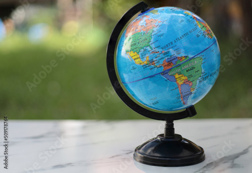 a world globe on white table in soft green nature background.