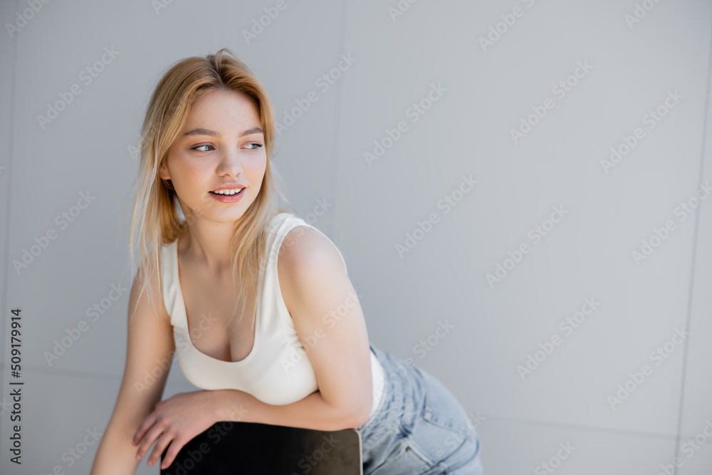 Cheerful young woman posing near chair at home. Cheerful young woman posing near chair at home.