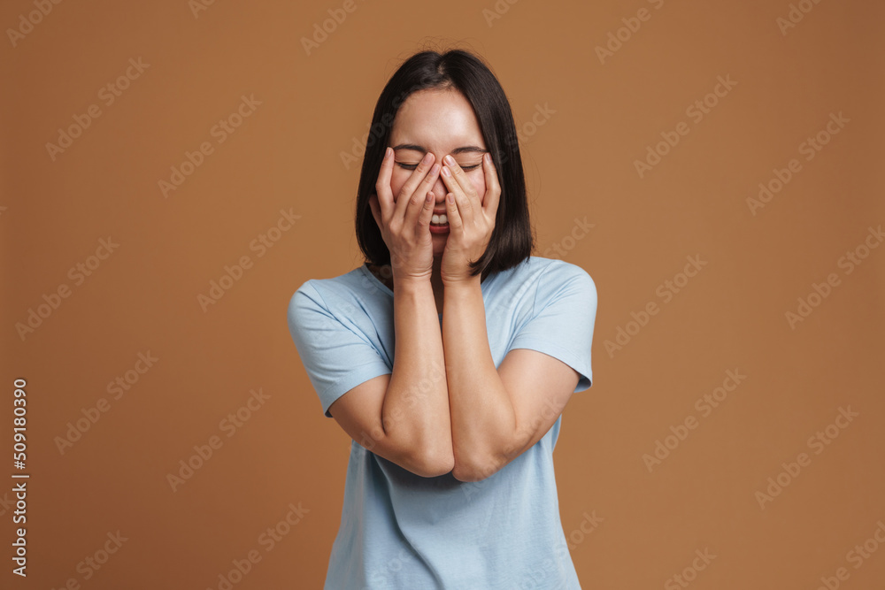 Young asian woman wearing t-shirt laughing and covering her face Young asian woman wearing t-shirt laughing and covering her face
