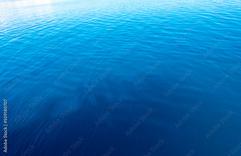 Obraz premium Clear water texture in blue and orange. Background of the ocean and the sea backlit by the sun. Natural water