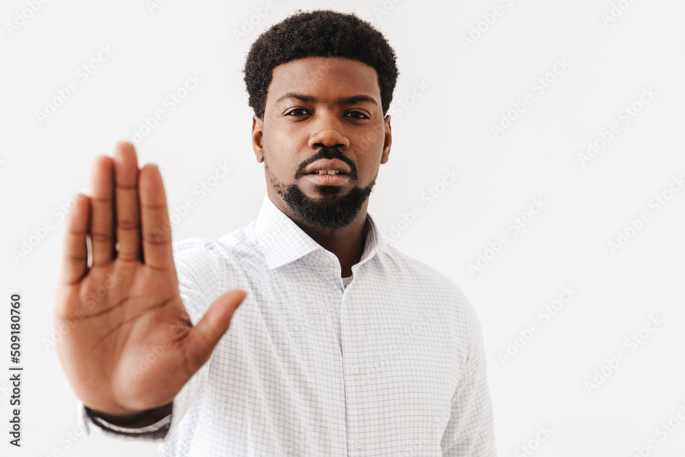 Black mid man wearing shirt showing stop gesture at camera