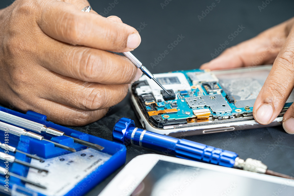 Technician repairing inside of mobile phone by soldering iron. Integrated Circuit. the concept of data, hardware, technology. Technician repairing inside of mobile phone by soldering iron. Integrated Circuit. the concept of data, hardware, technology.