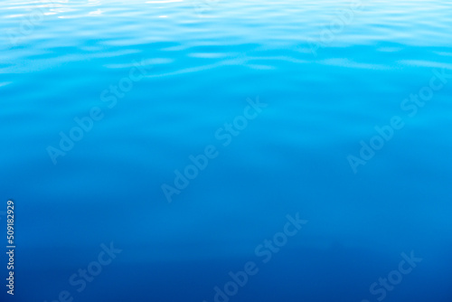 Clear water texture in blue and orange. Background of the ocean and the sea backlit by the sun. Natural water