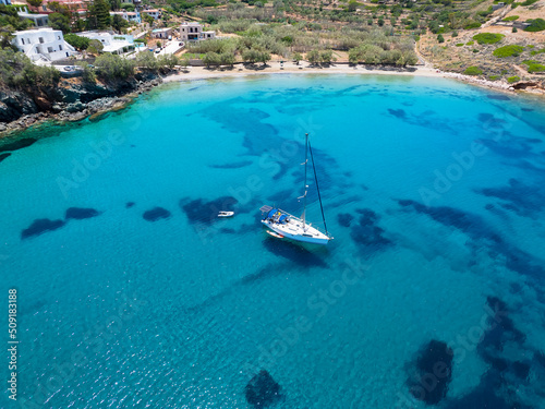 Fototapeta Naklejka Na Ścianę i Meble -  Aerial view of the beautiful Lotos Beach next to Kini bay at Syros island, Greece, with a sailboat moored over turquoise sea