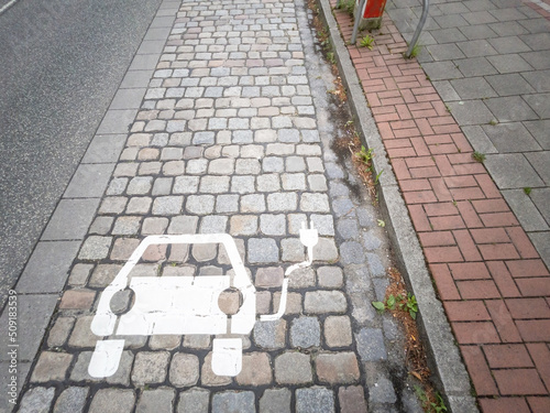 Electric car charging sign painted on paving stones on a city street. 