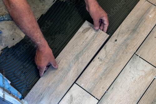 Wood tile flooring. A worker lays floor tiles.