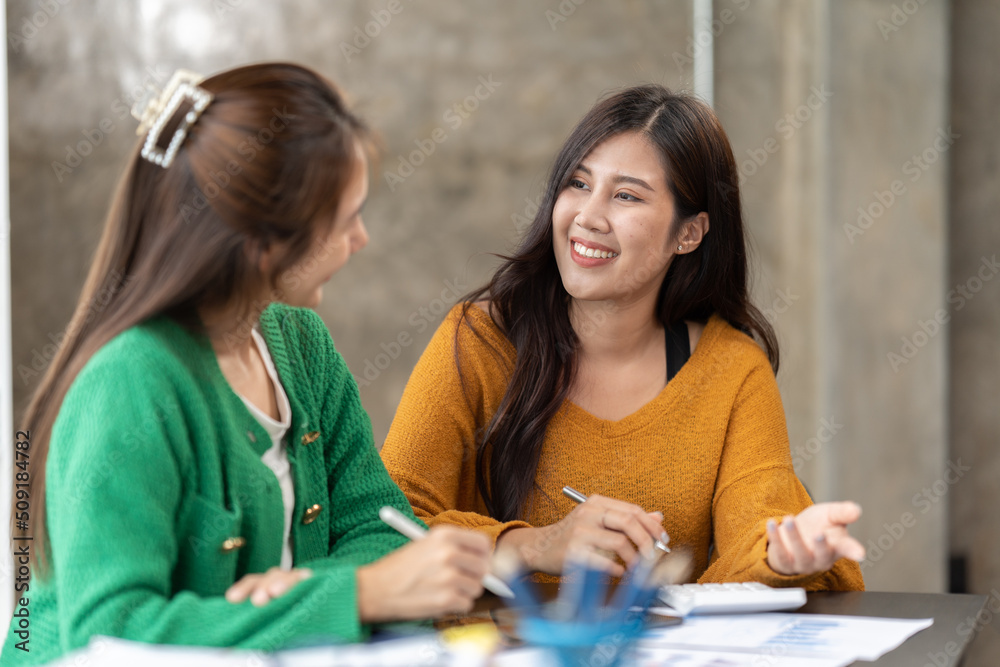 Two asian women discussing business projects in a office while having coffee. Startup, ideas and brain storm concept. Two asian women discussing business projects in a office while having coffee. Startup, ideas and brain storm concept.