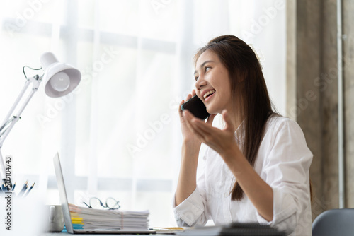 Woman using laptop and smartphone in office. Beautiful girl looking at mobile phone. Entrepreneur, businesswoman, freelance worker, student working on computer at home. Business, technology concept