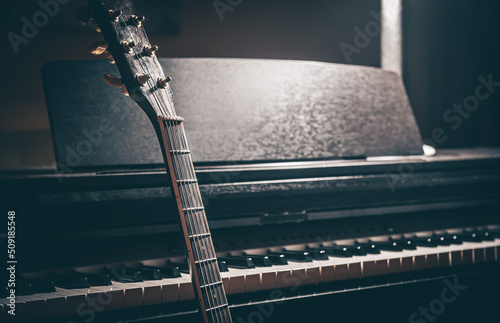 Guitar and electronic piano in a dark room close-up.