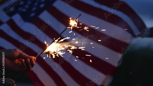 Happy 4th of July Independence Day, Hand holding Sparkler fireworks USA celebration with American flag waving nature outdoor background. Concept Independence Day,Fireworks,Sparkler,Memorial,Veterans