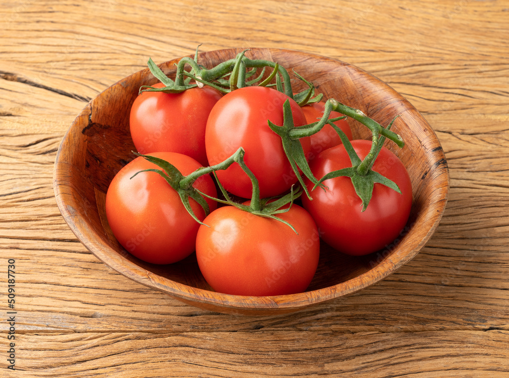 Red tomatoes in a bowl over wooden table Red tomatoes in a bowl over wooden table