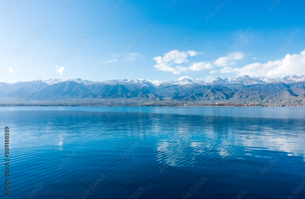 Sverny shore of Lake Issyk-Kul, Kyrgyzstan. View from the ship to the shore. Blue water of a mountain lake.