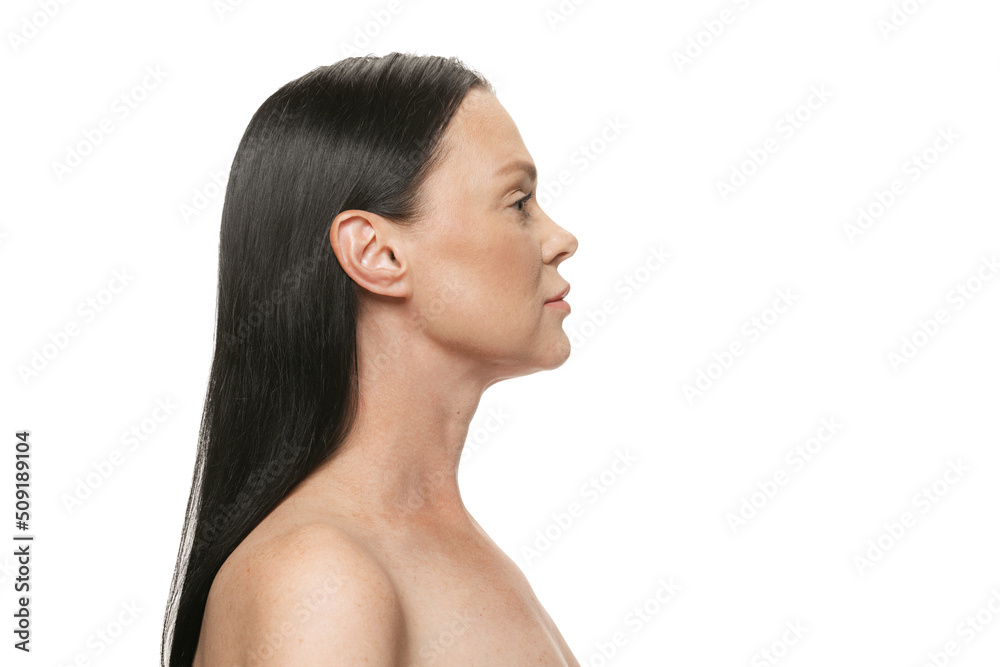 Profile view of middle age beautiful woman with well-kept skin and long black hair on white background. Cosmetics, spa, age-related changes, face lifting and skin care concept Profile view of middle age beautiful woman with well-kept skin and long black hair on white background. Cosmetics, spa, age-related changes, face lifting and skin care concept
