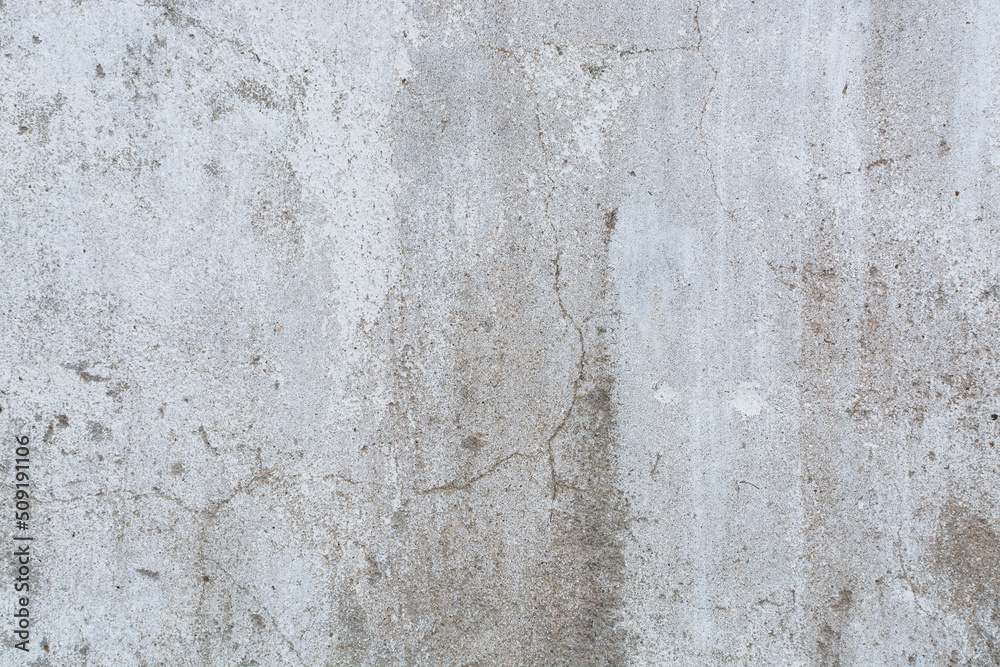 The background of an old concrete wall painted white with cracks. The texture of the plaster.
