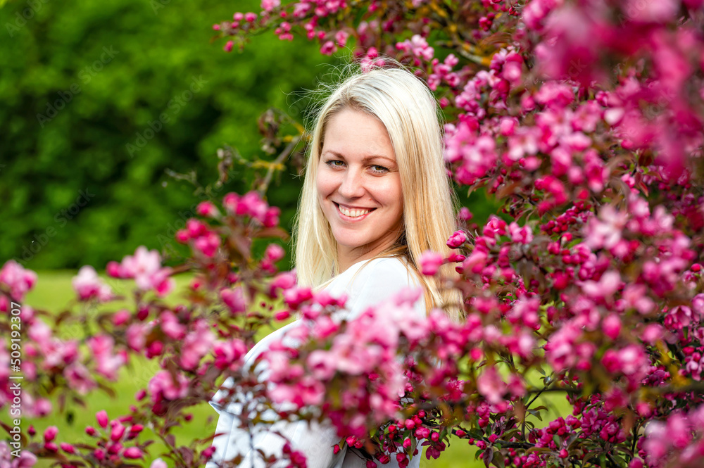 closeup portrait of a smiling blonde woman in a blossoming garden in spring, selective focus closeup portrait of a smiling blonde woman in a blossoming garden in spring, selective focus