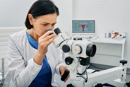 Experienced gynecologist woman sitting near colposcopy in her gynecological office. Profession of gynecologist for women's health photo