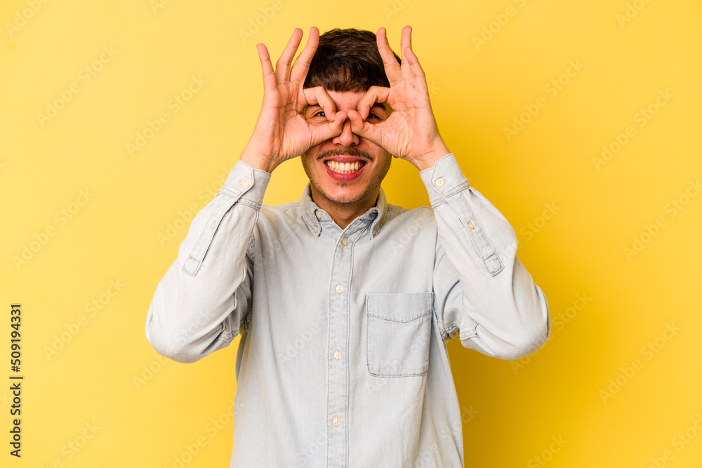 Young caucasian man isolated on yellow background excited keeping ok gesture on eye.