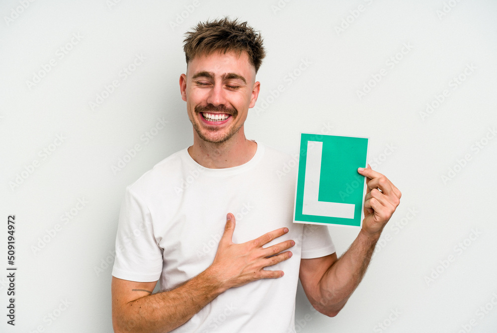 Young caucasian man holding L placard isolated on white background laughing and having fun. Young caucasian man holding L placard isolated on white background laughing and having fun.