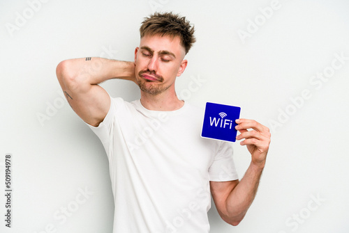 Young caucasian man holding wifi placard isolated on white background touching back of head, thinking and making a choice. © Asier