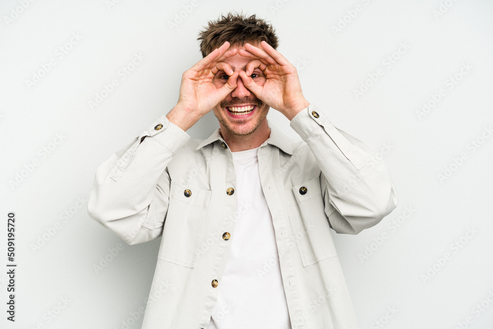 Young caucasian man isolated on white background showing okay sign over eyes Young caucasian man isolated on white background showing okay sign over eyes