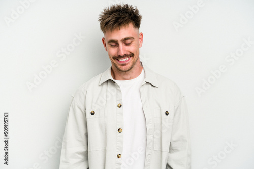 Young caucasian man isolated on white background laughs and closes eyes, feels relaxed and happy. © Asier