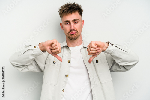 Young caucasian man isolated on white background showing a dislike gesture, thumbs down. Disagreement concept.