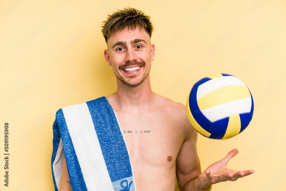 Young caucasian man playing volleyball isolated on yellow background