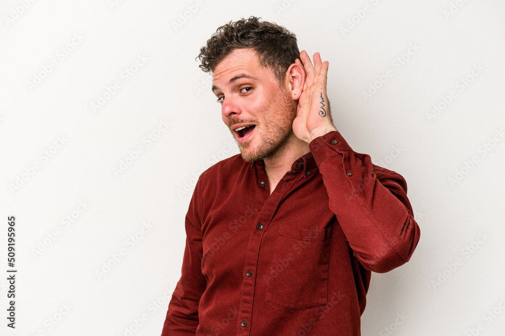 Young caucasian man isolated on white background trying to listening a gossip. Young caucasian man isolated on white background trying to listening a gossip.