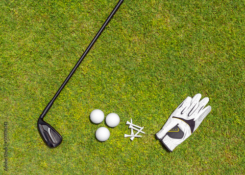 Top view of golf equipment on green grass on a golf course. Flat lay of golf club, balls, glove, tees