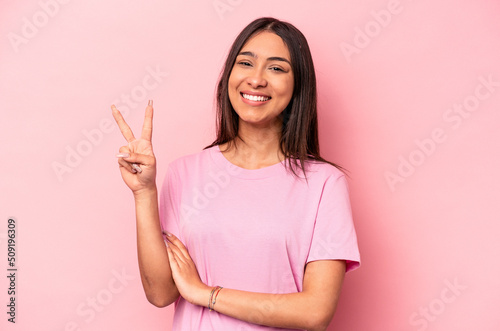 Young hispanic woman isolated on pink background showing number two with fingers. © Asier