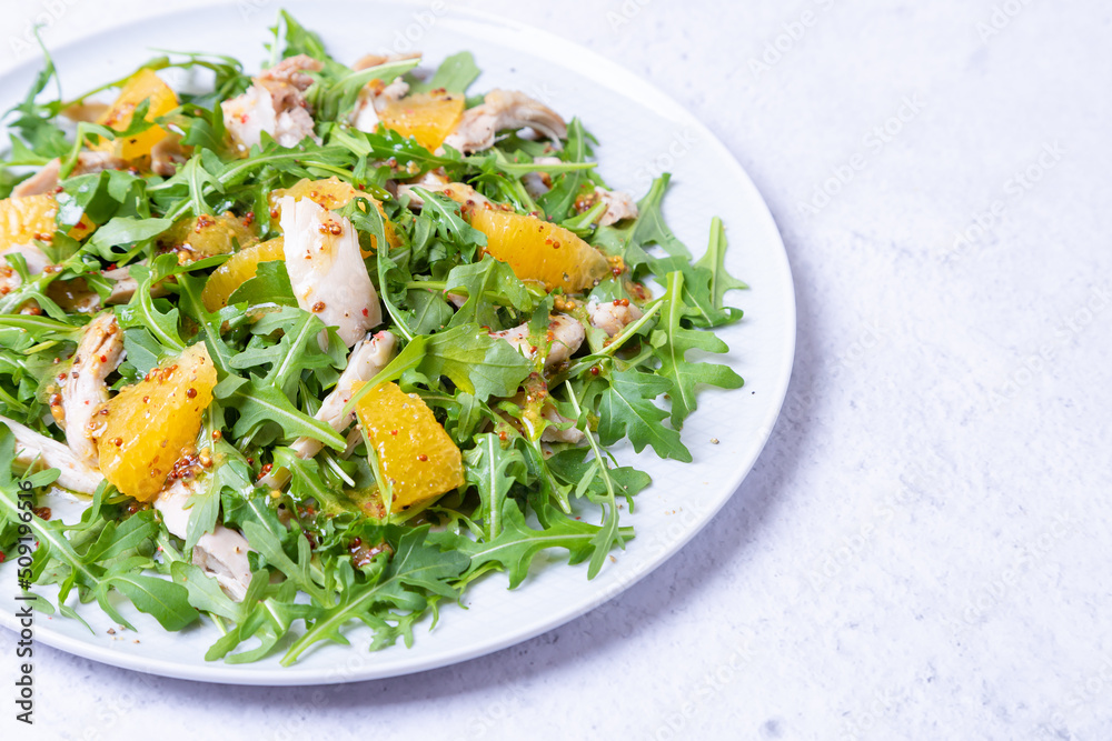 Salad with chicken, oranges and arugula. Dressing with olive oil and grain mustard. Close-up.