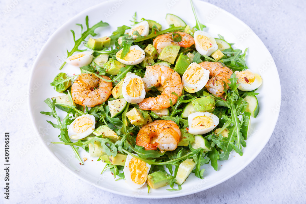 Salad with shrimp, avocado, cucumber, quail eggs and arugula. Mediterranean traditional cuisine. Close-up. Salad with shrimp, avocado, cucumber, quail eggs and arugula. Mediterranean traditional cuisine. Close-up.