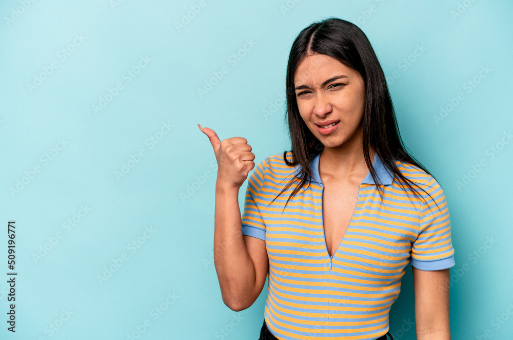 Young hispanic woman isolated on blue background shocked pointing with index fingers to a copy space. - obrazy, fototapety, plakaty 
