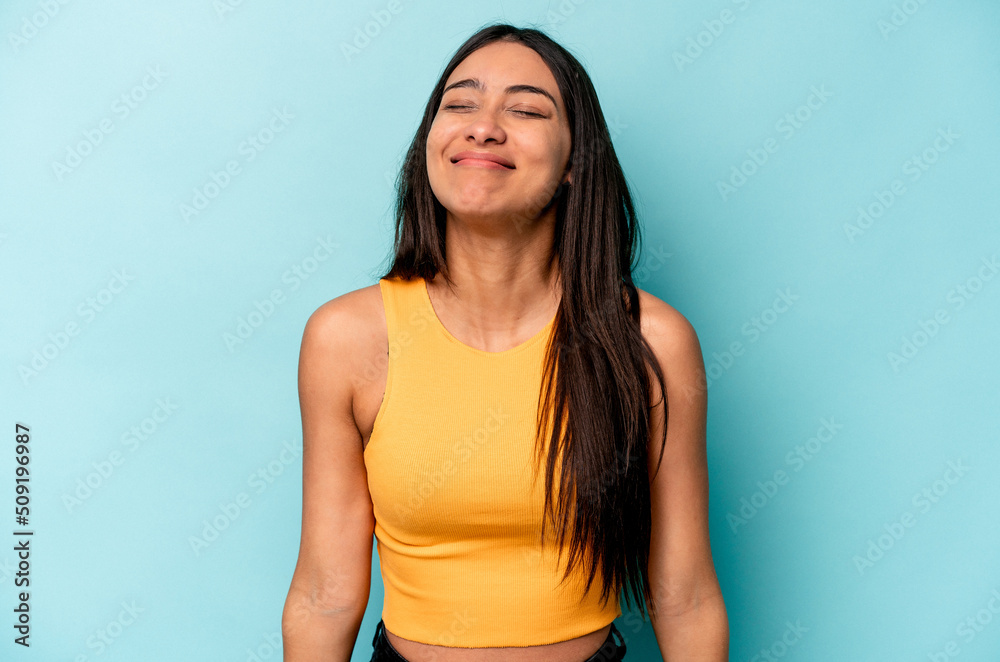 Young hispanic woman isolated on blue background laughs and closes eyes, feels relaxed and happy. Young hispanic woman isolated on blue background laughs and closes eyes, feels relaxed and happy.