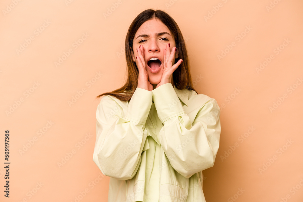 Young hispanic woman isolated on beige background shouting excited to front. Young hispanic woman isolated on beige background shouting excited to front.