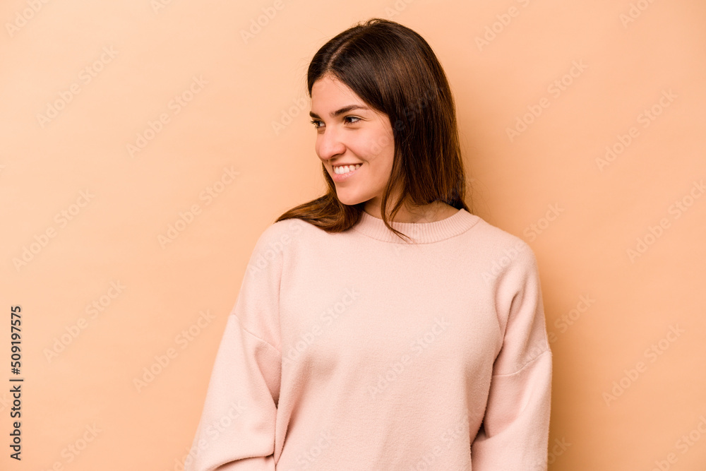 Young hispanic woman isolated on beige background laughs happily and has fun keeping hands on stomach. Young hispanic woman isolated on beige background laughs happily and has fun keeping hands on stomach.