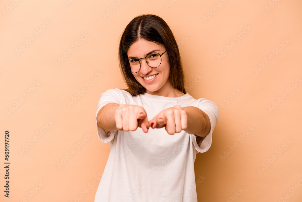 Young hispanic woman isolated on beige background pointing to front with fingers. Young hispanic woman isolated on beige background pointing to front with fingers.