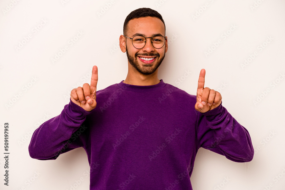 Young hispanic man isolated on white background indicates with both fore fingers up showing a blank space. Young hispanic man isolated on white background indicates with both fore fingers up showing a blank space.